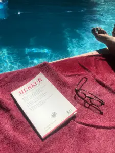 Abbildung: Merkur-Heft auf einem Handtuch neben einem Pool